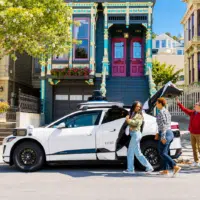 Taxi autonome Waymo dans une rue colorée de San Francisco avec des passagers devant des maisons victoriennes