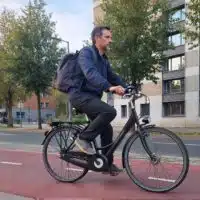 Un cycliste adulte roule sur un vélo électrique en milieu urbain, illustrant un usage quotidien.