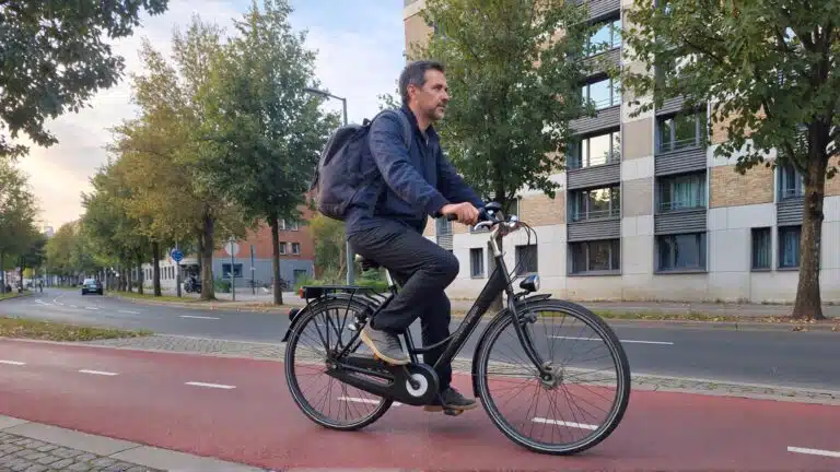 Un cycliste adulte roule sur un vélo électrique en milieu urbain, illustrant un usage quotidien.