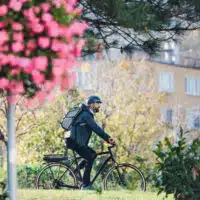 Vue latérale d'un homme d'affaires hipster se rendant au travail à vélo en ville.