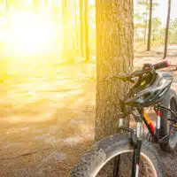 Vélo électrique stationné en forêt, avec un casque posé sur le guidon, lors d’une sortie en milieu naturel.