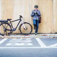 Vélo électrique stationné contre un mur en milieu urbain, avec un homme à proximité.