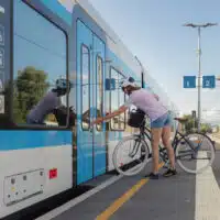 Cycliste montant dans un train avec son vélo sur un quai de gare, dans un trajet combinant vélo et transport ferroviaire.