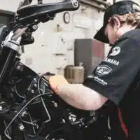 Technicien inspectant une moto en atelier dans le cadre du contrôle technique des deux-roues motorisés