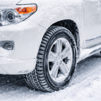 Gros plan sur un pneu hiver d’un véhicule roulant sur la neige, illustrant l’adhérence en conditions hivernales