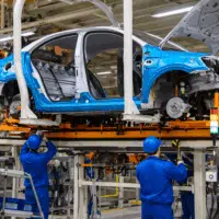 Chaîne d’assemblage automobile en usine avec des opérateurs travaillant sur une carrosserie en cours de montage