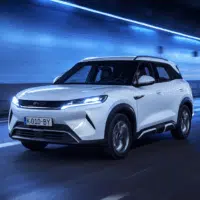 SUV électrique BYD blanc circulant dans un tunnel éclairé en bleu, illustrant l’arrivée de modèles potentiellement éligibles au bonus écologique en France.