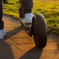 Gros plan sur une trottinette électrique grande roue circulant sur un chemin pavé, illustrant la stabilité et le confort de conduite en milieu urbain.