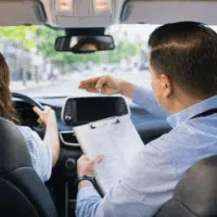 Élève en leçon de conduite avec un moniteur d’auto-école à bord d’un véhicule lors d’une formation au permis de conduire.