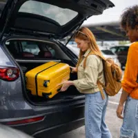 voyageuses chargeant des bagages dans une voiture de location pour un voyage