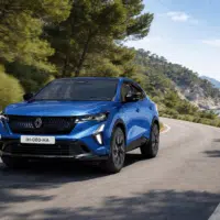 Renault Rafale SUV hybride roulant sur une route côtière avec paysage méditerranéen en arrière-plan.