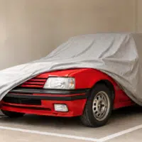 Peugeot 205 rouge des années 80 sous housse de protection