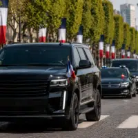 SUV présidentiel électrique noir sur une avenue pavoisée aux couleurs françaises